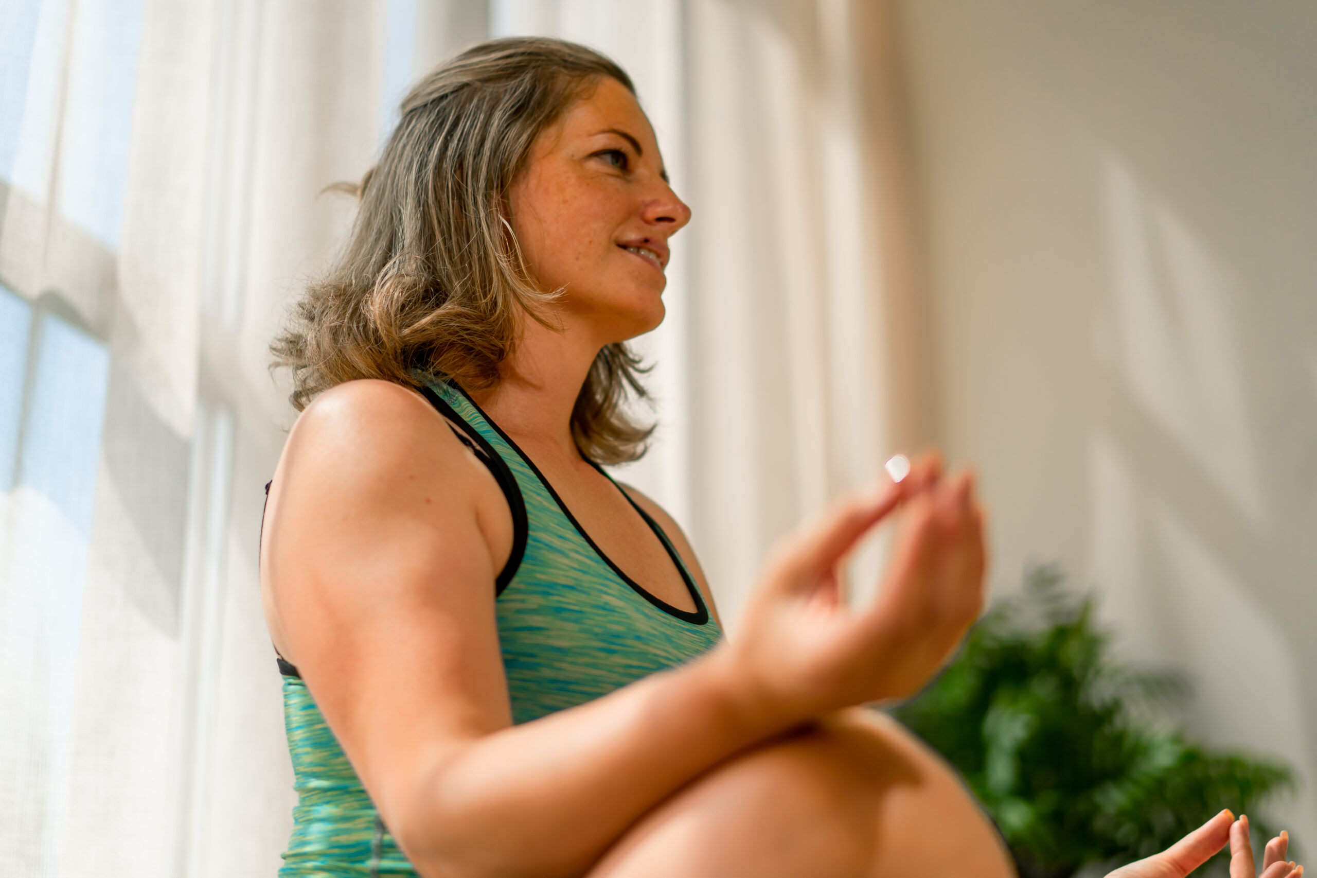 close-up shot of a hand on the leg of a girl who sits in sportswear in lotus position and meditates in a yoga room