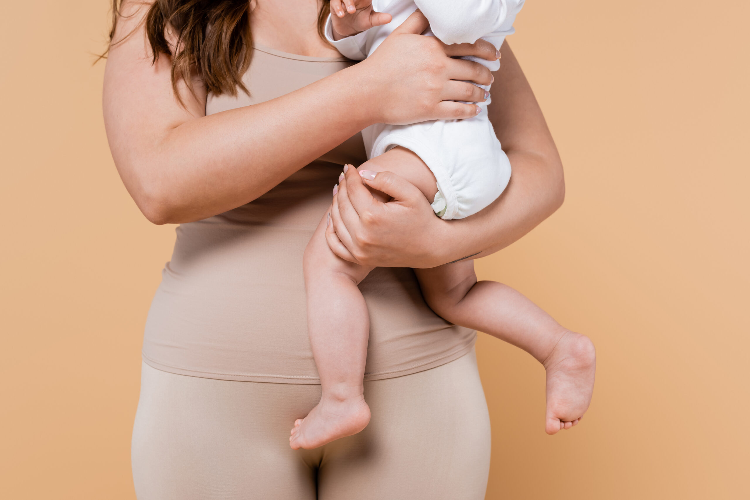 Cropped view of body positive woman hugging child isolated on beige