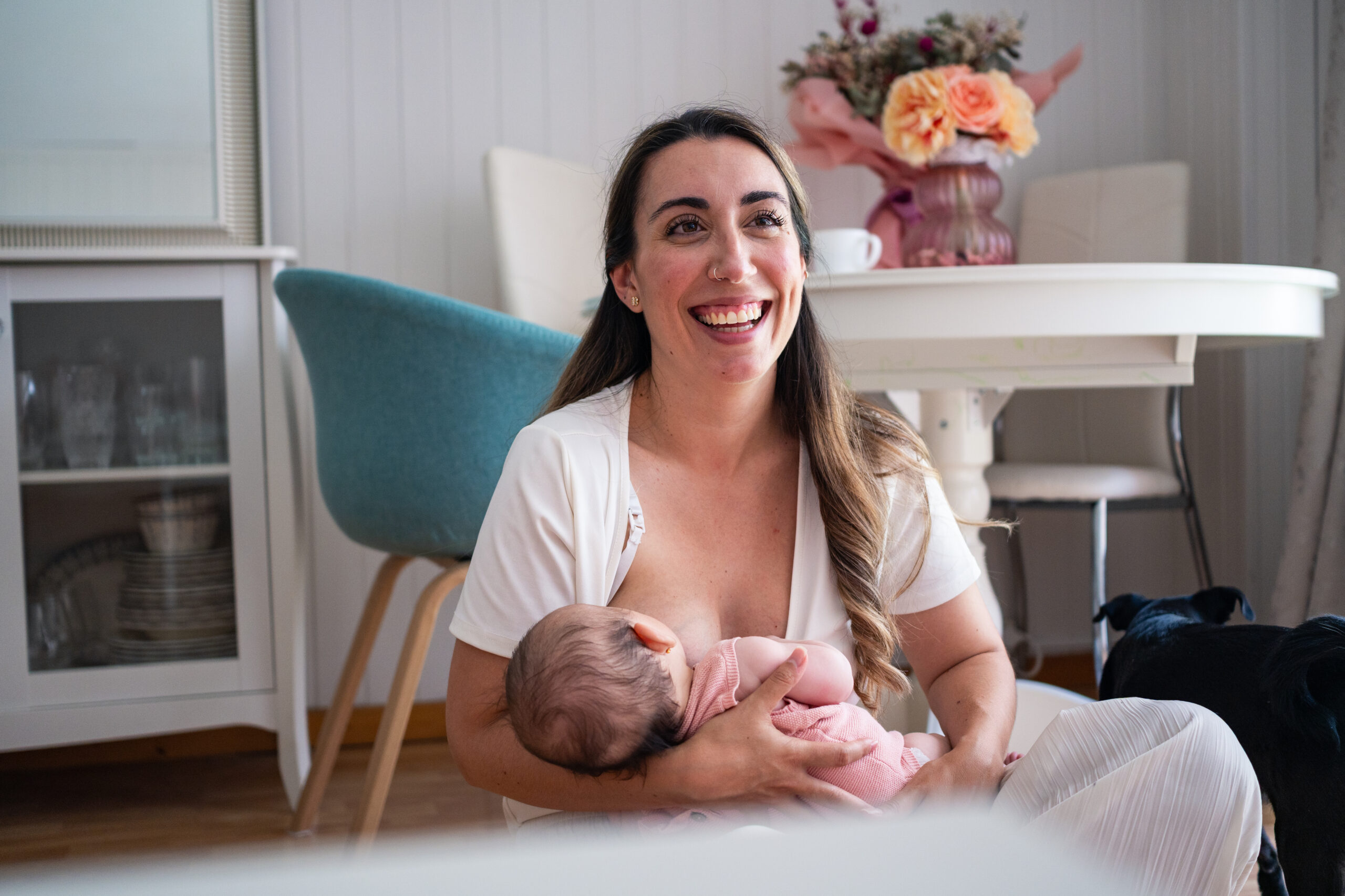 Smiling mother is happily breastfeeding her baby in a warm and inviting living room.